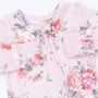 A close-up of a baby long-sleeve top in light pink with a watercolor floral print featuring red, white, and purple flowers with green leaves.