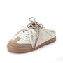 A low-top slip-on sneaker in off-white and beige suede with a brown gum sole, featuring a star-shaped side detail and matching brown laces, shown on a white background.