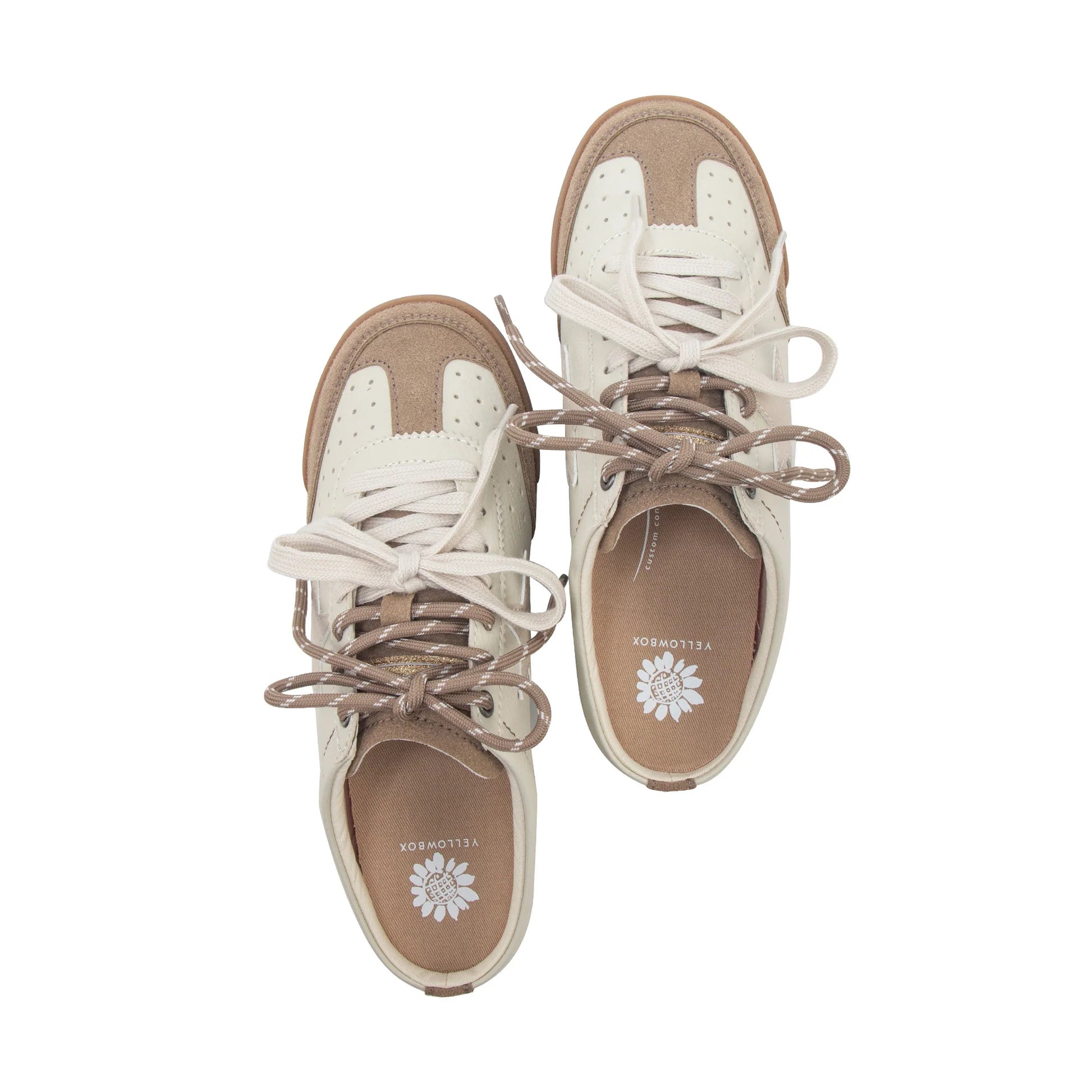 A pair of low-top lace-up sneakers shown from a top-down view on a plain white background. The shoes feature cream and tan panels with matching beige laces and a tan insole.