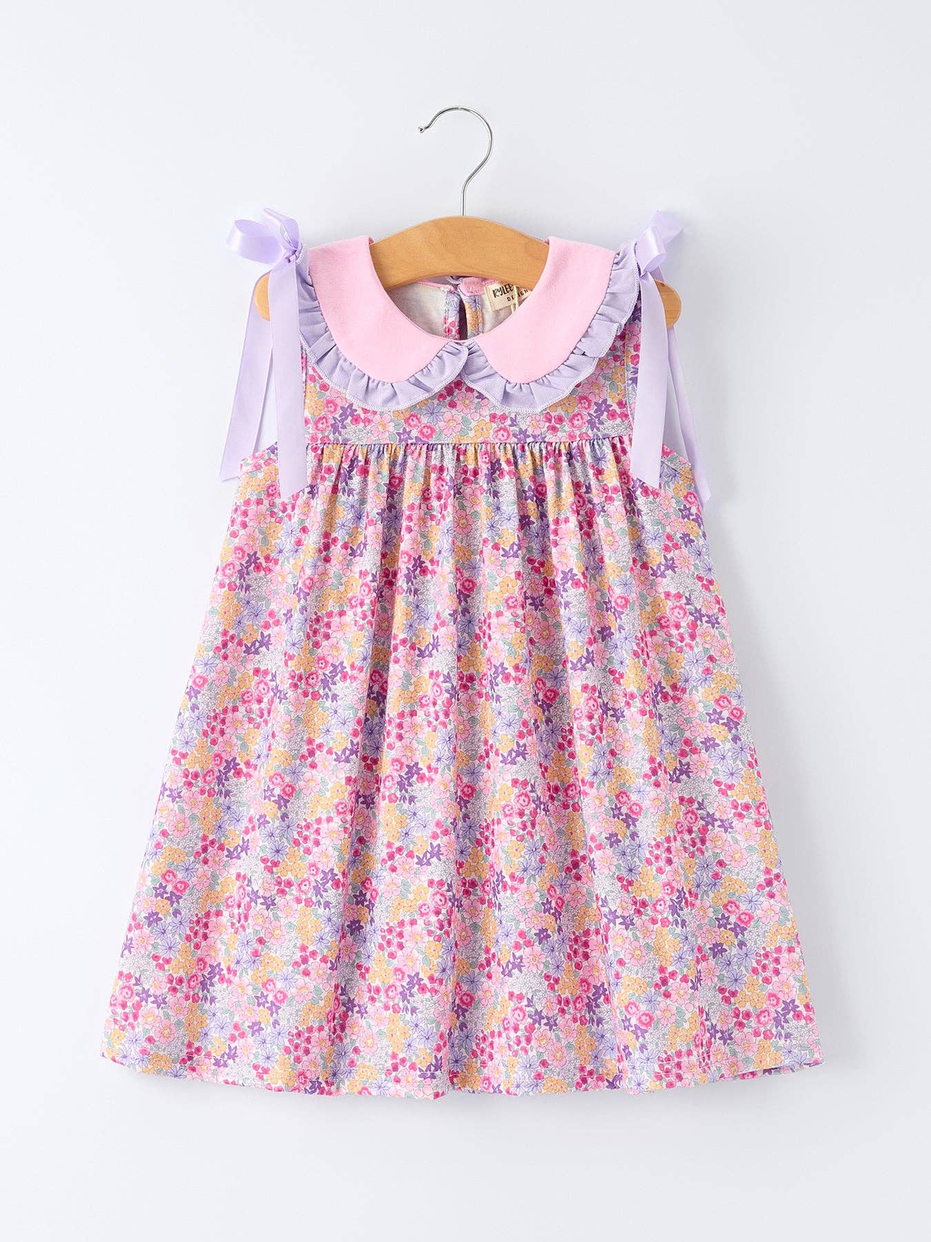 Floral dress with a pink collar on a hanger against a white background