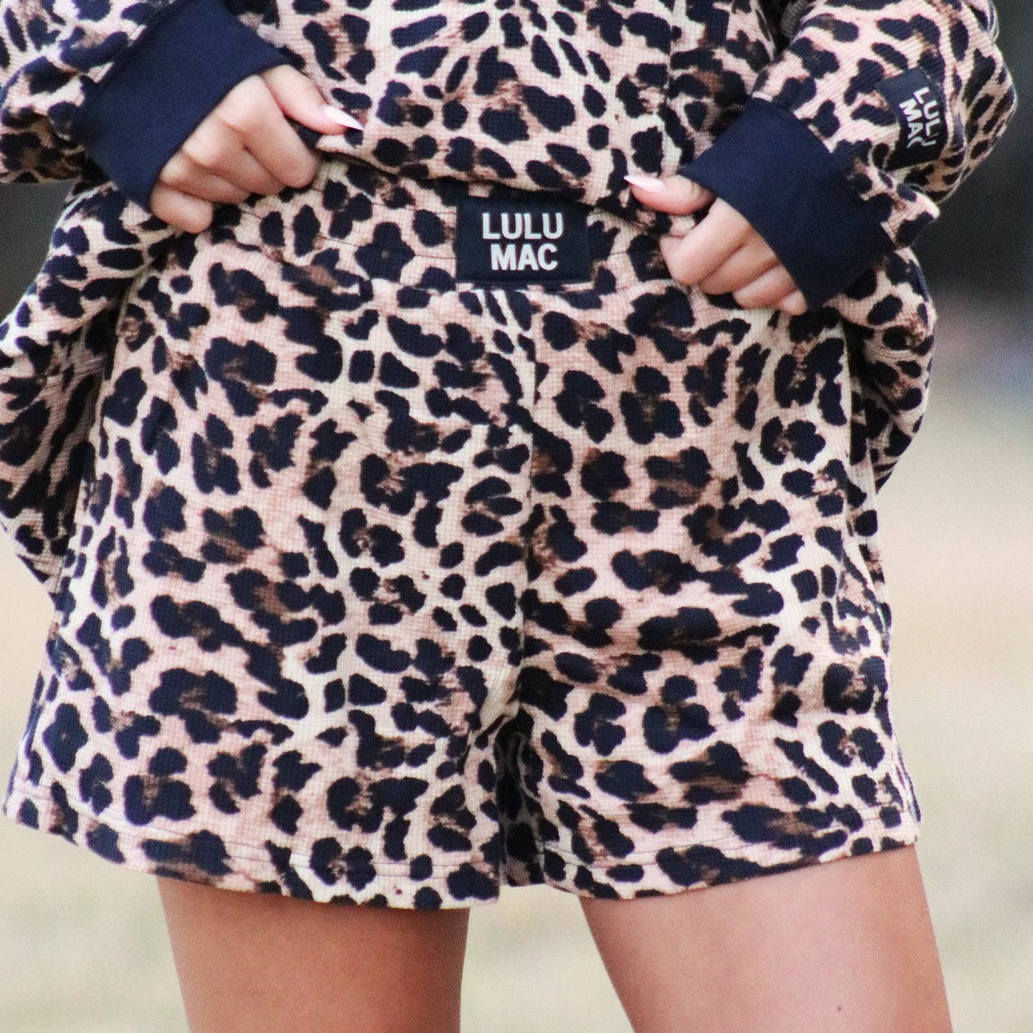 Leopard print shorts with navy cuffs and 'LULU MAC' label on a blurred background