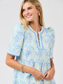 Woman wearing a blue floral dress against a gray background
