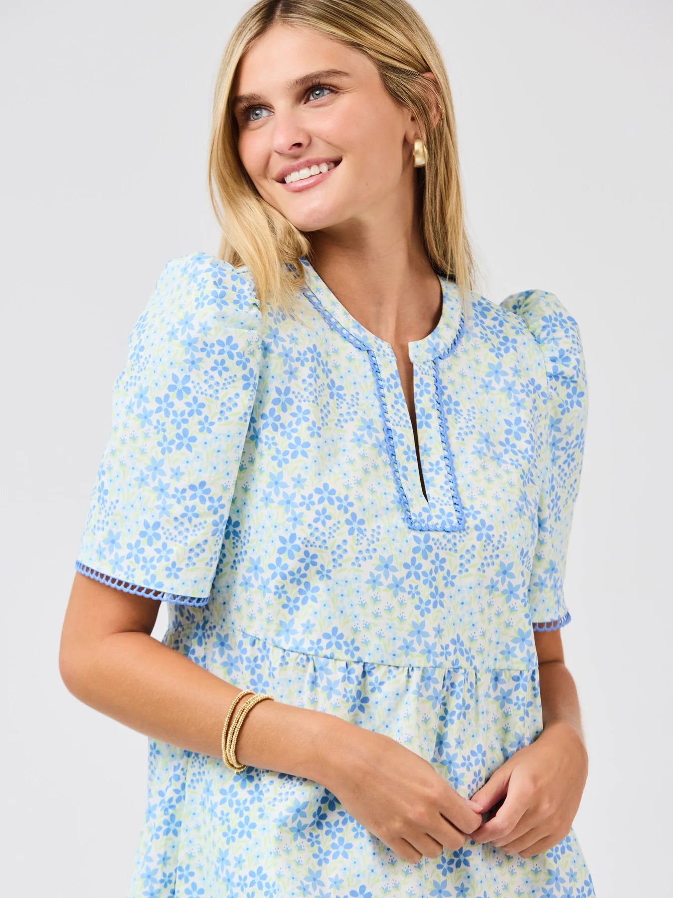 Woman wearing a blue floral dress against a gray background