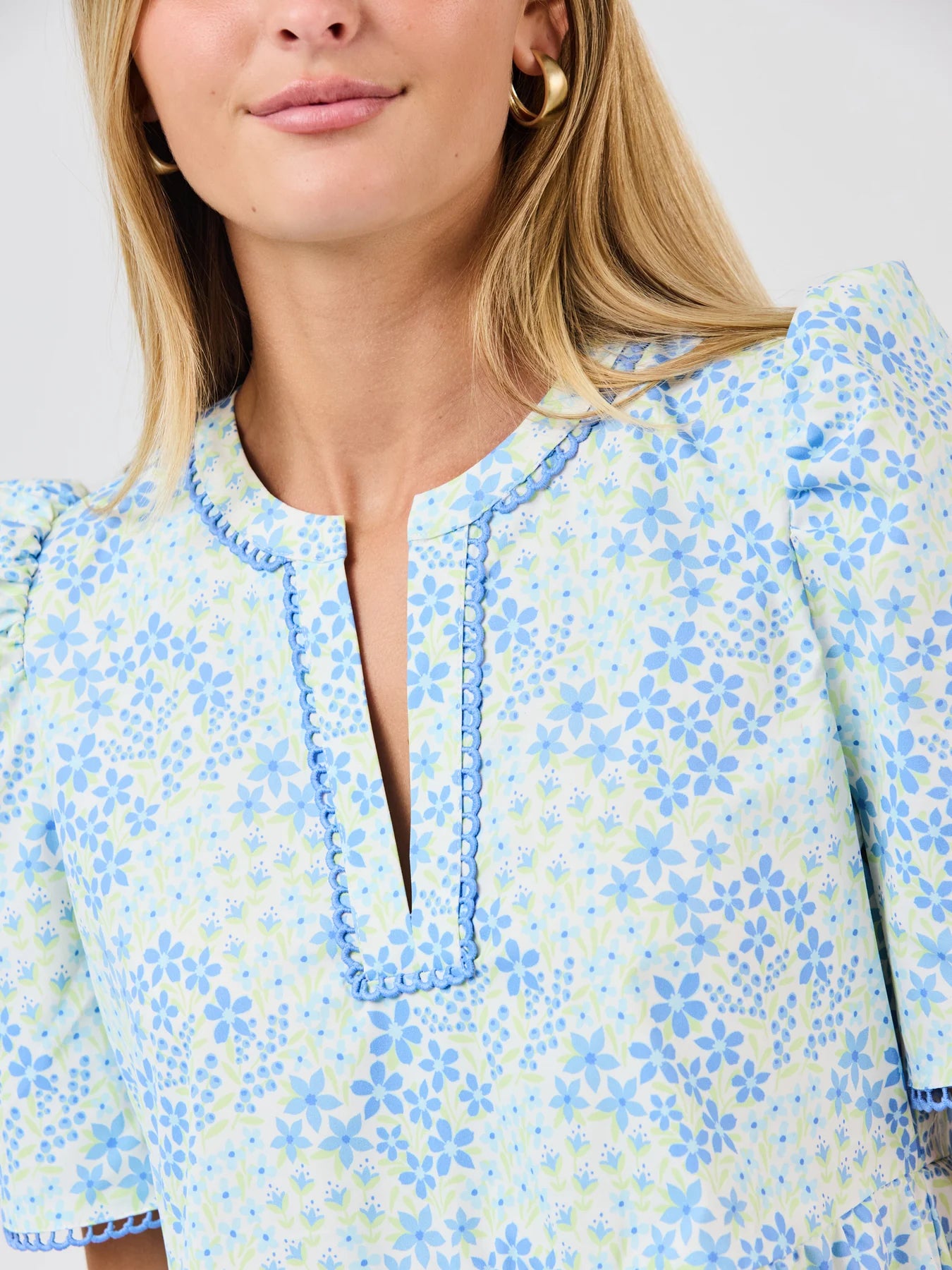 Close-up of a woman wearing a blue floral blouse against a white background
