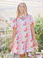 Woman wearing a floral dress in an outdoor setting with plants and flowers.