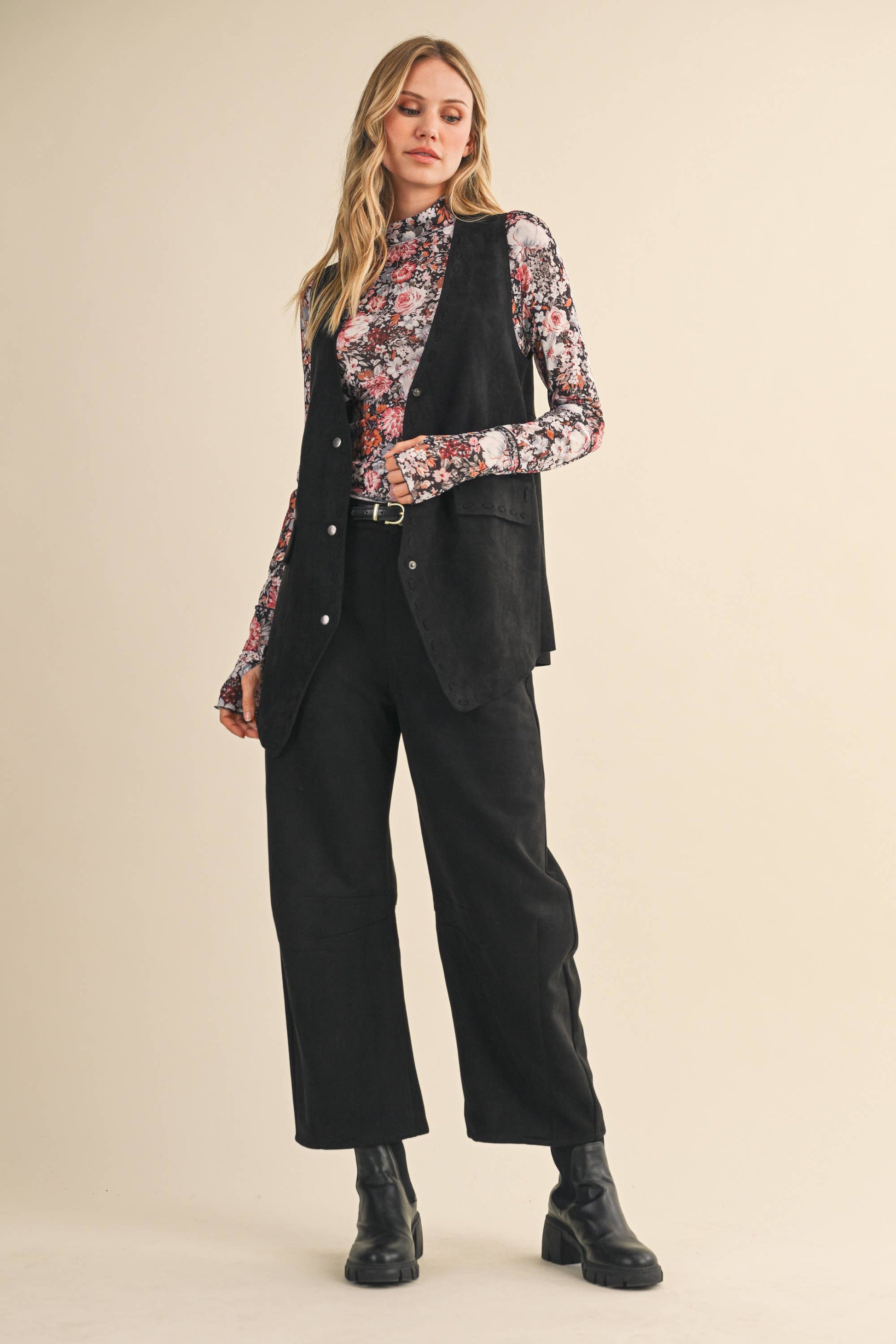 Woman wearing a black suit with a floral blouse on a beige background