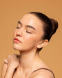Woman with a bun hairstyle against a beige background