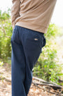 Navy pants with a logo on the pocket worn by a person in an outdoor setting
