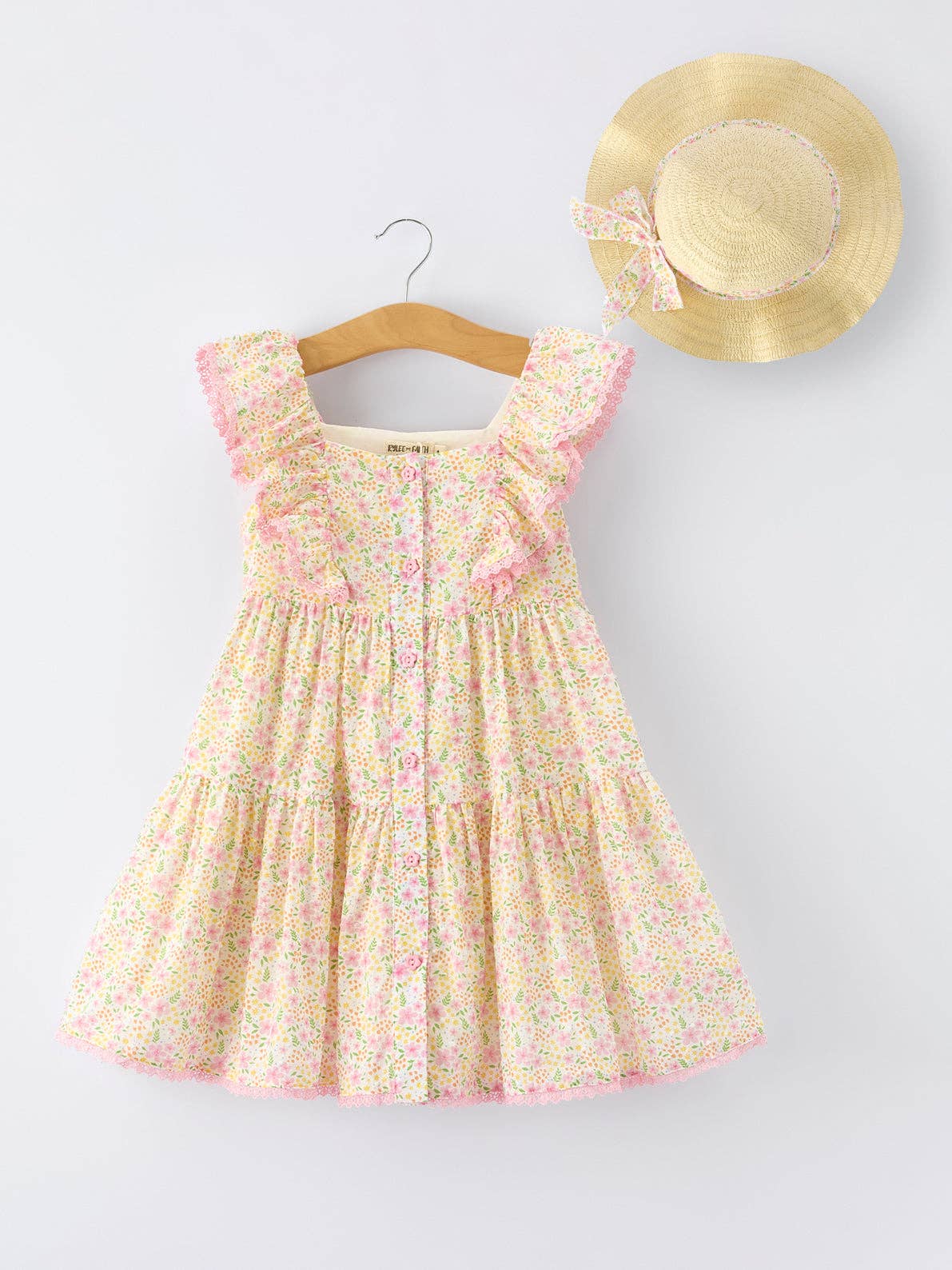 Floral dress on a hanger with a straw hat on a white background