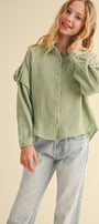 Girl wearing a green textured shirt and light blue jeans on a beige background