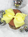 Yellow hair bow on a wooden block with disco balls around