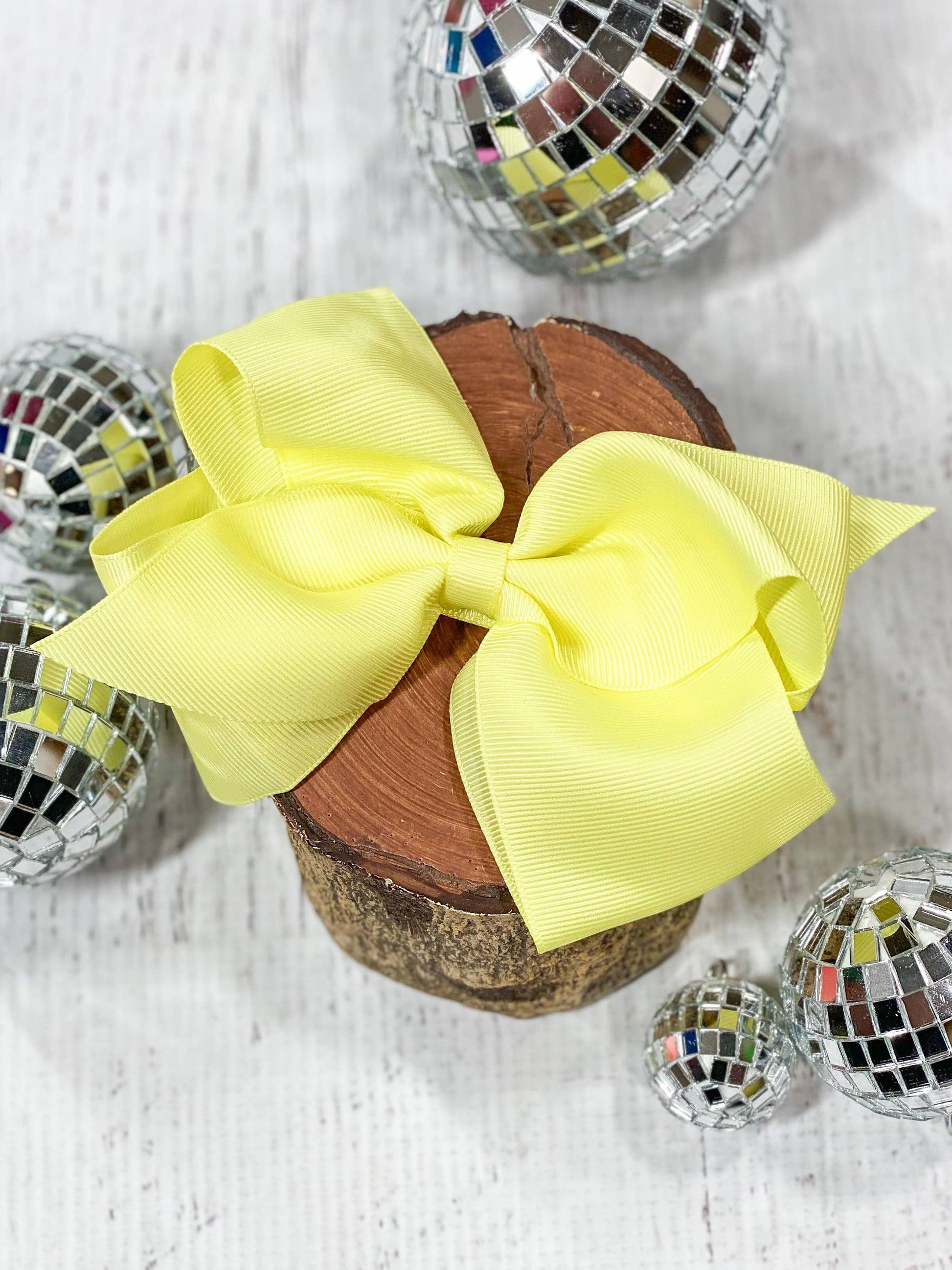 Yellow hair bow on a wooden block with disco balls around