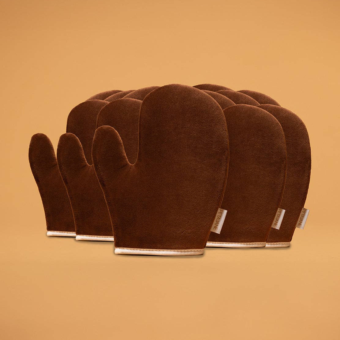 Set of brown self tanning mitts on a beige background