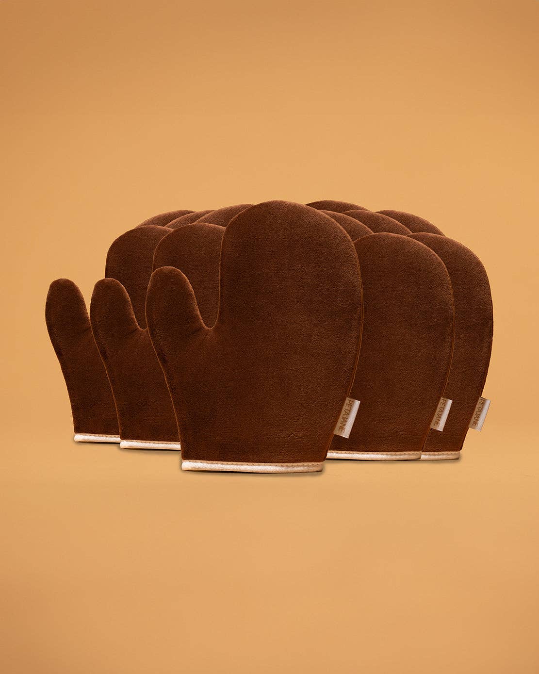 Set of brown self tanning mitts on a beige background