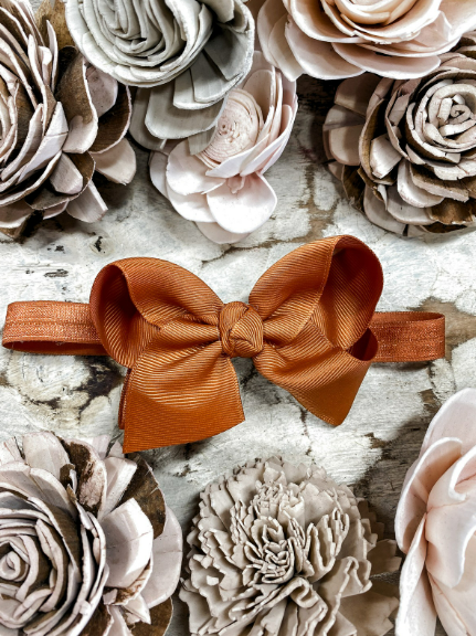 Brown bow headband on a textured surface with floral decorations