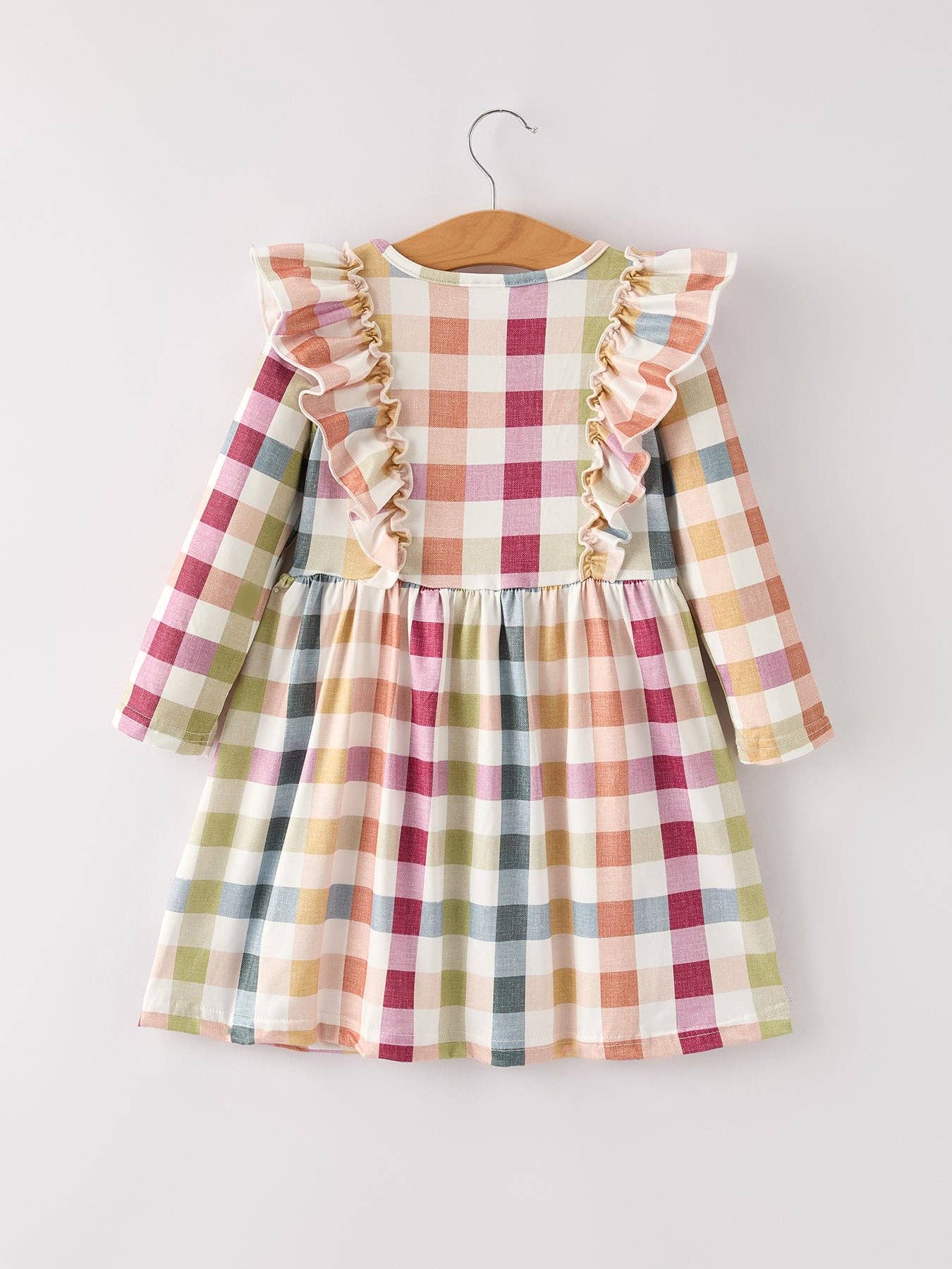 Checkered dress with ruffled sleeves on a hanger against a white background
