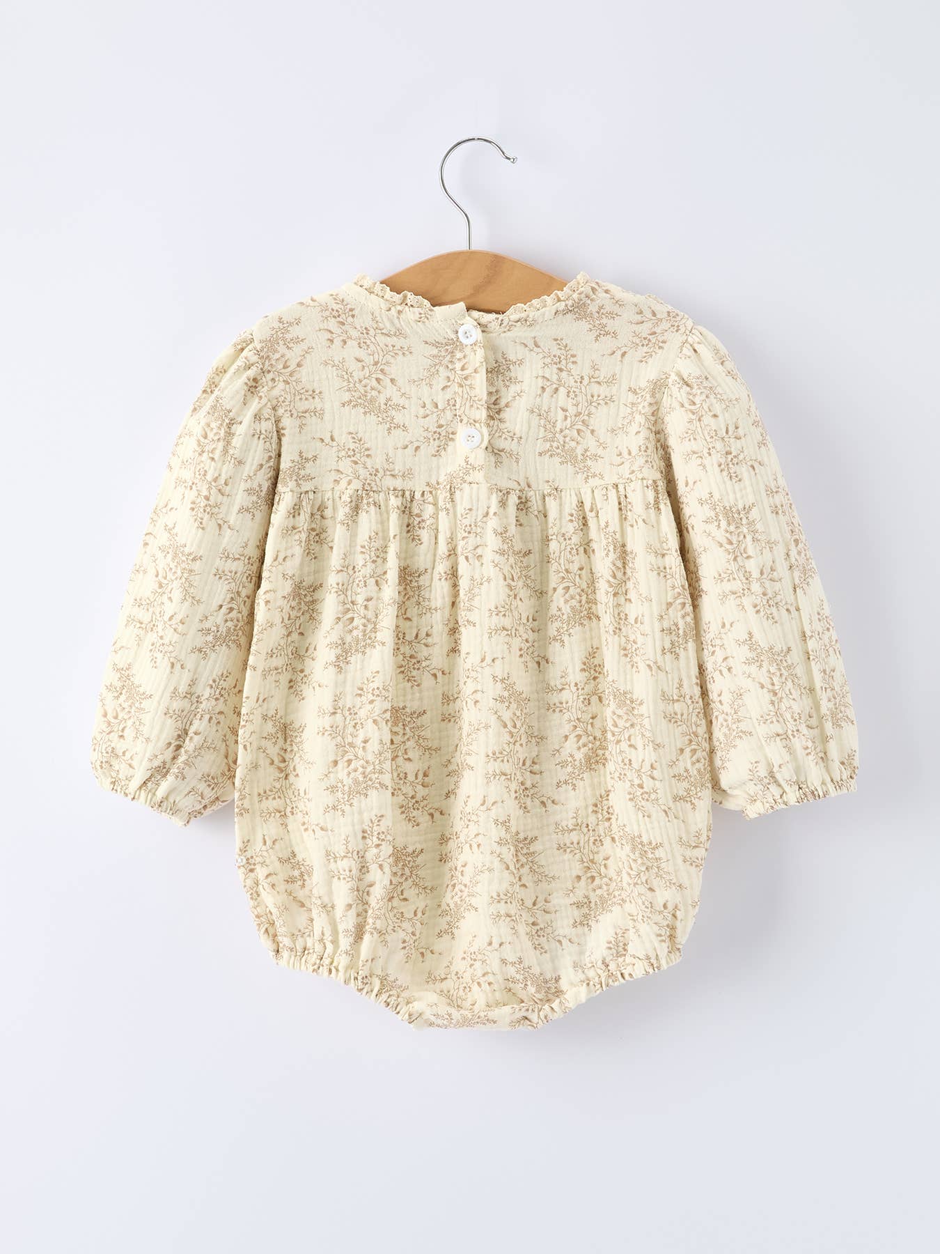 Beige lace baby dress on a hanger against a white background