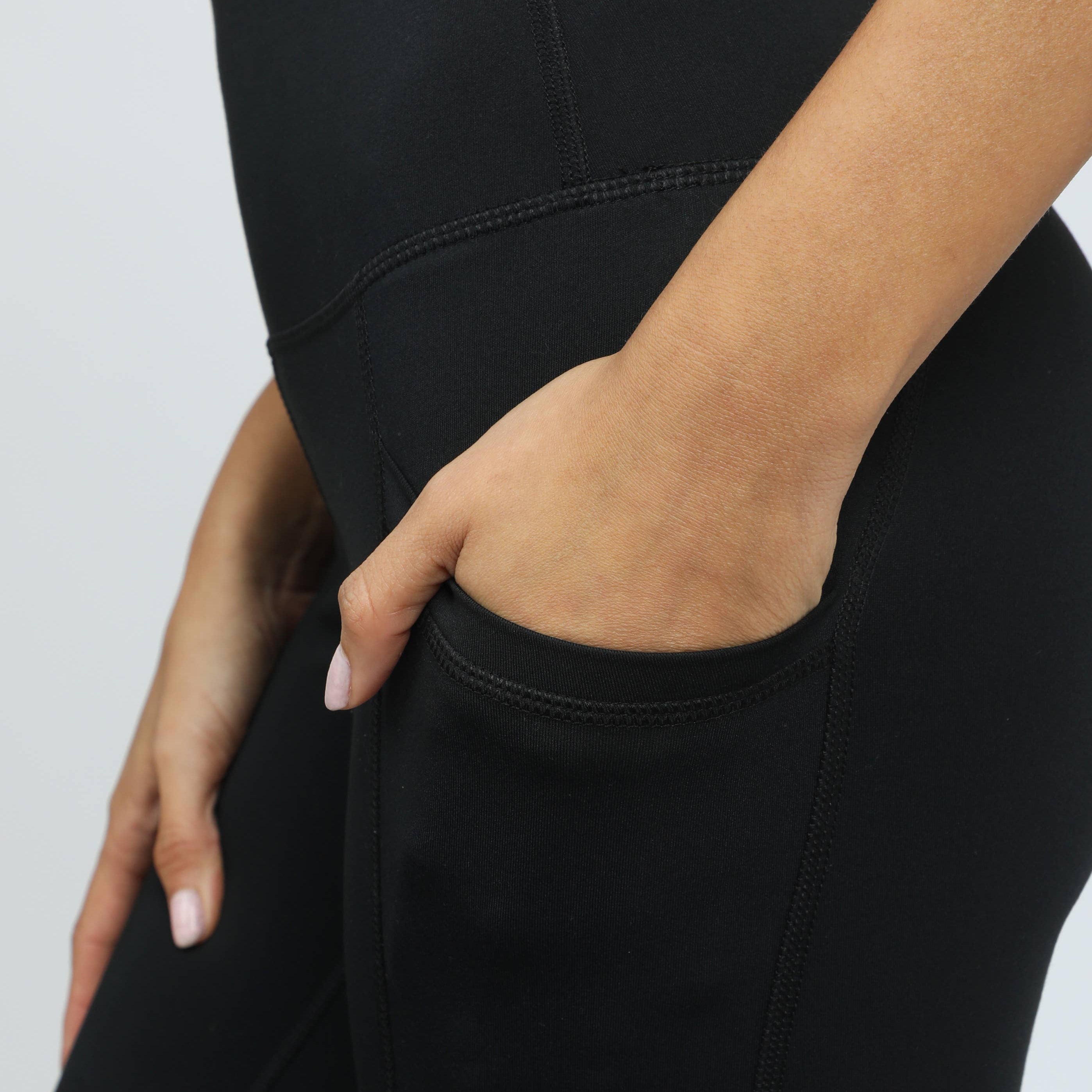 Black high-waisted leggings worn by a person on a light gray background