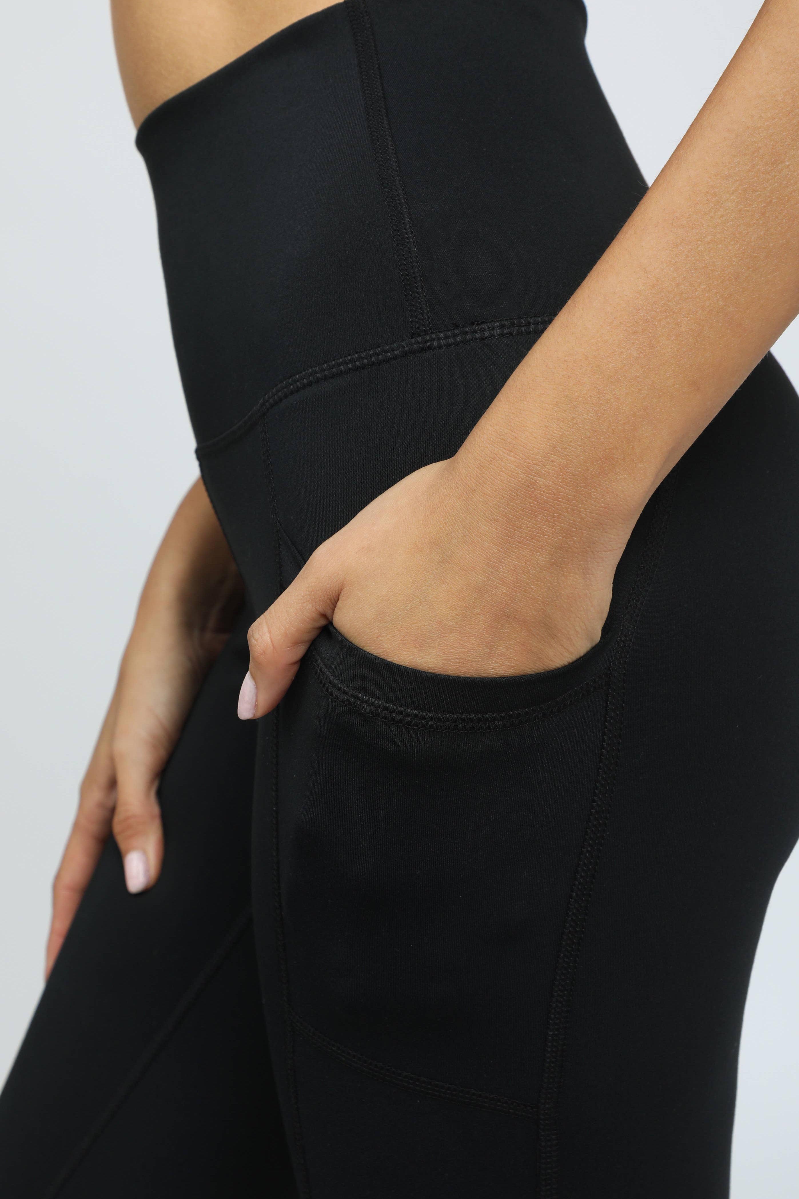 Black high-waisted leggings worn by a person on a light gray background