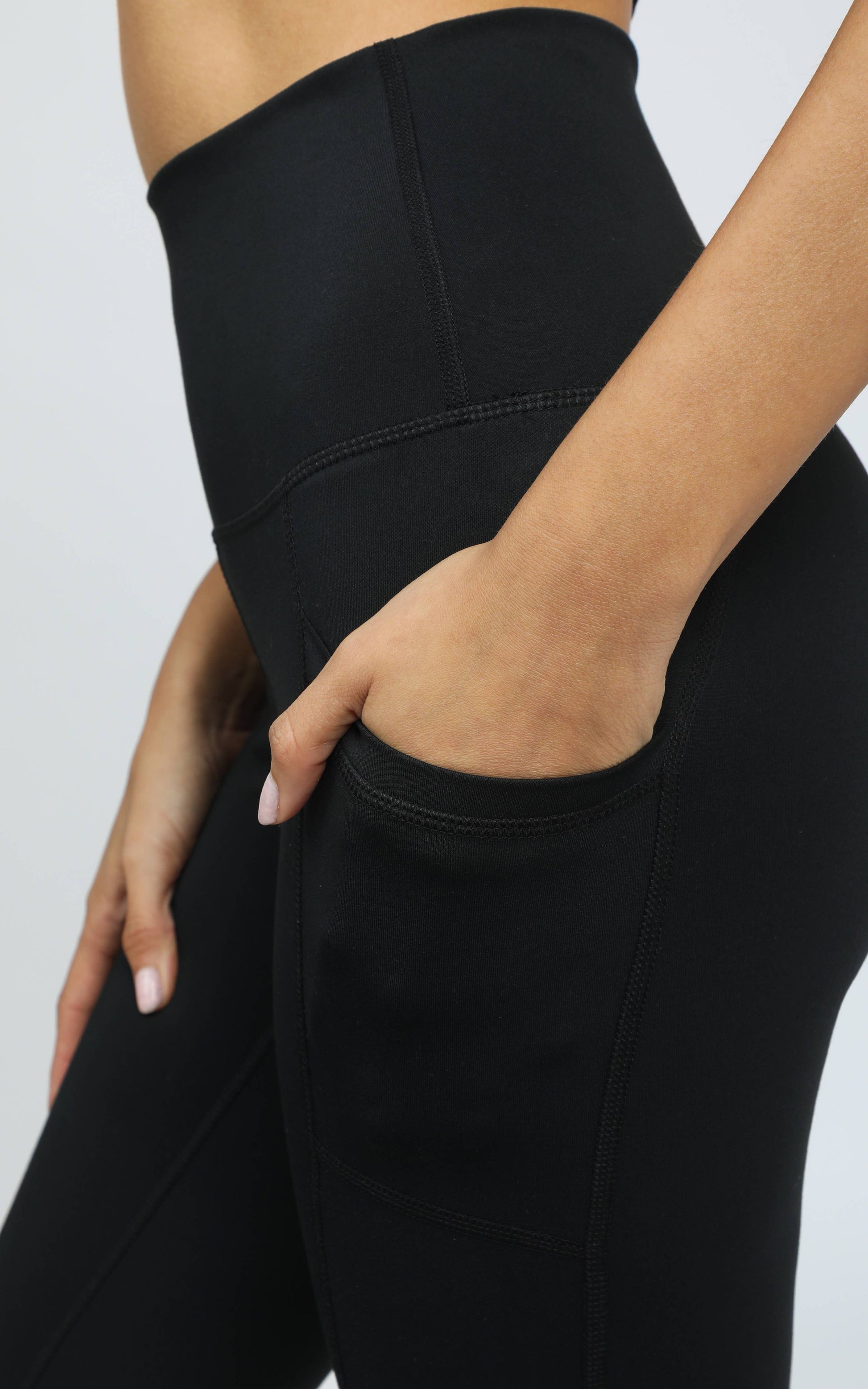 Black high-waisted leggings worn by a person on a light gray background