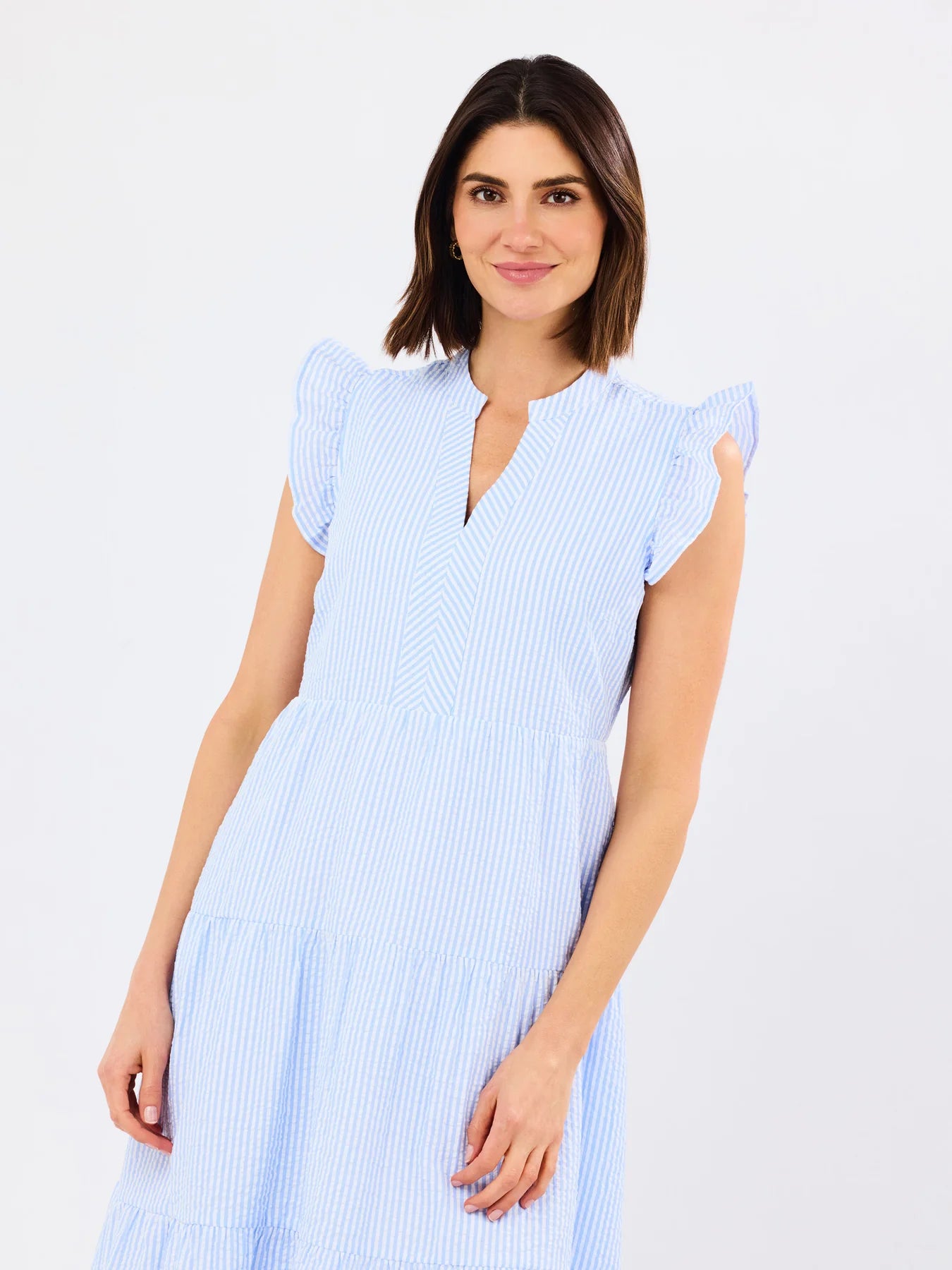 Woman wearing a light blue dress with ruffled sleeves on a white background