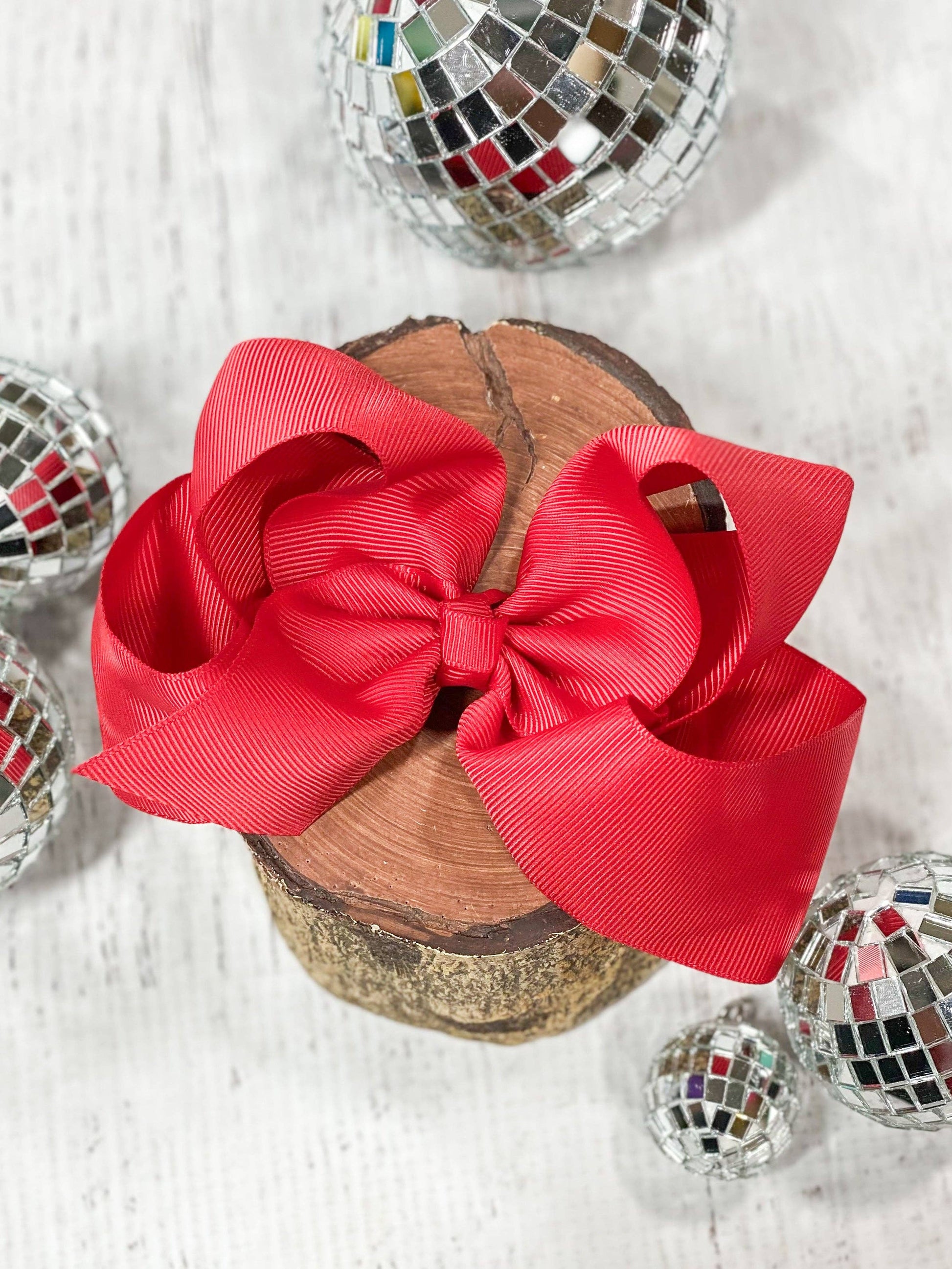 Red bow on a wooden block with disco balls in the background
