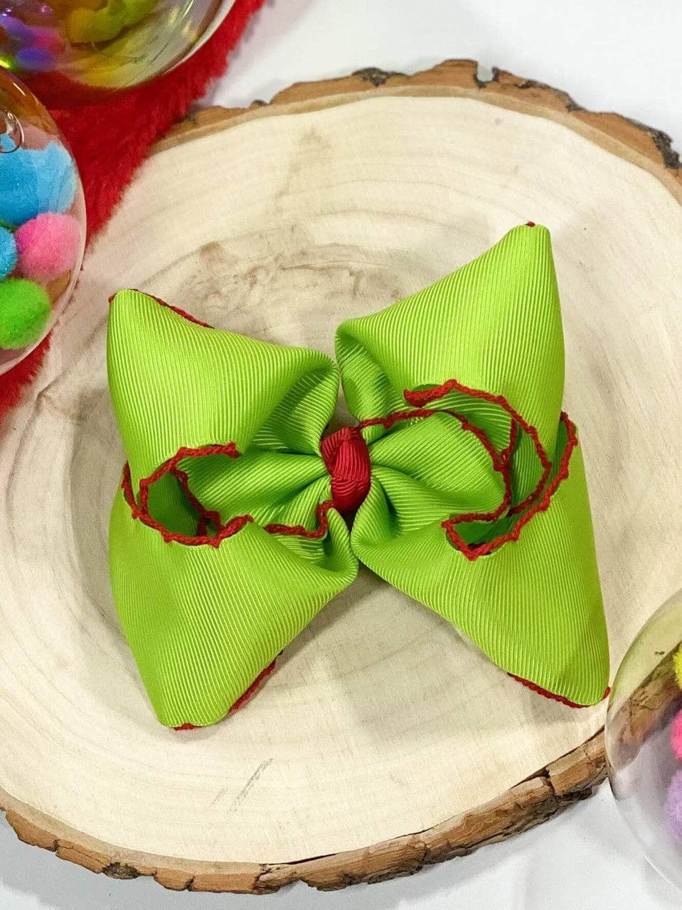 Green hair bow with red accents on a wooden surface