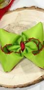 Green hair bow with red accents on a wooden surface