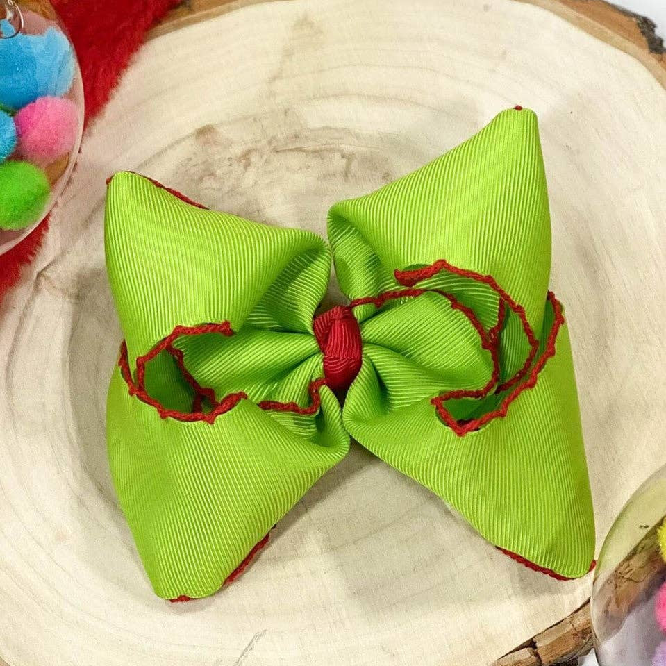 Green hair bow with red accents on a wooden surface