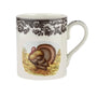 A white ceramic coffee mug featuring a black floral border pattern and a central illustration of a brown and gold turkey on a yellow background.