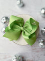 Green bow on a white plate with silver decorative elements in the background