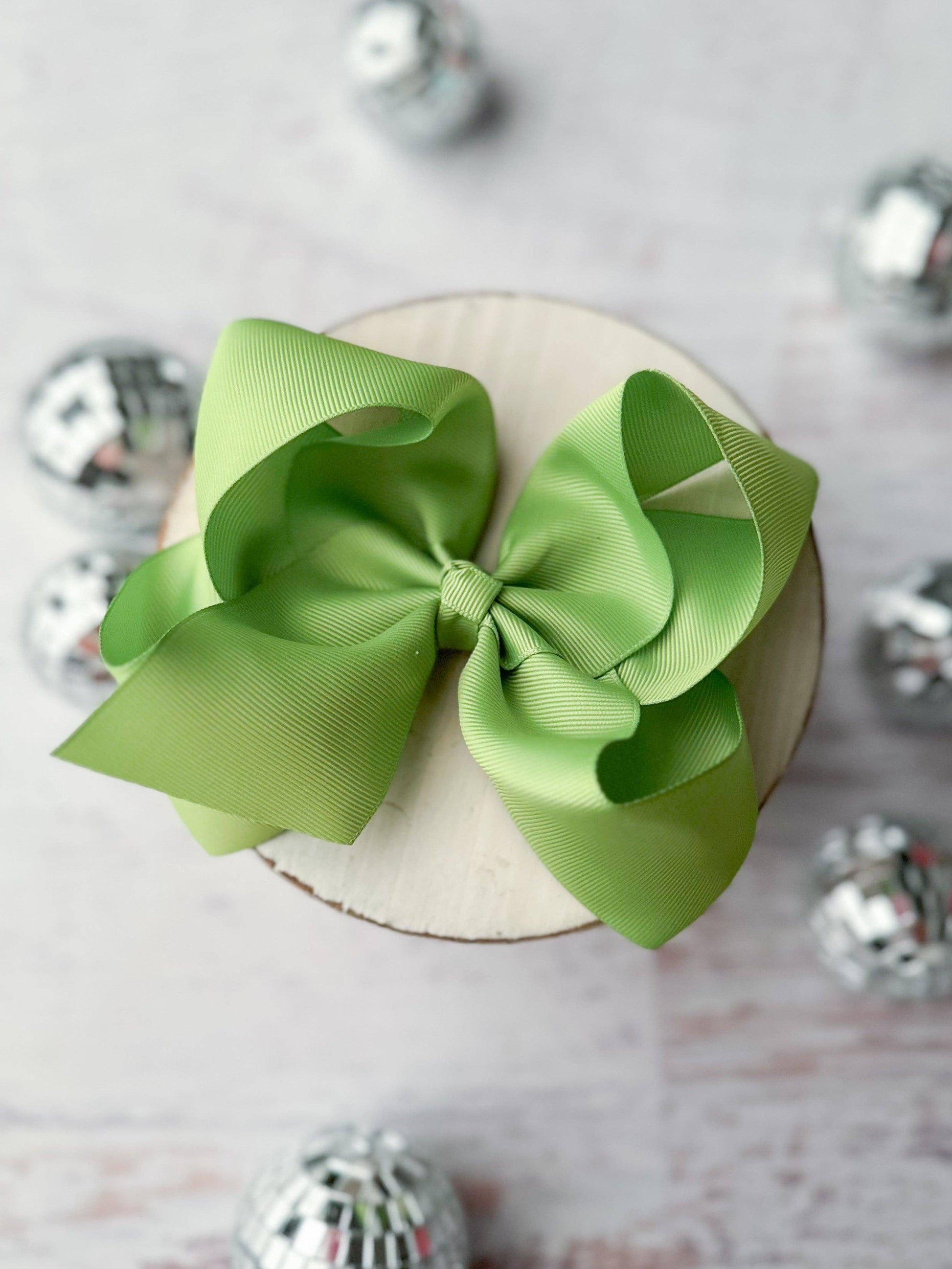 Green bow on a white plate with silver decorative elements in the background