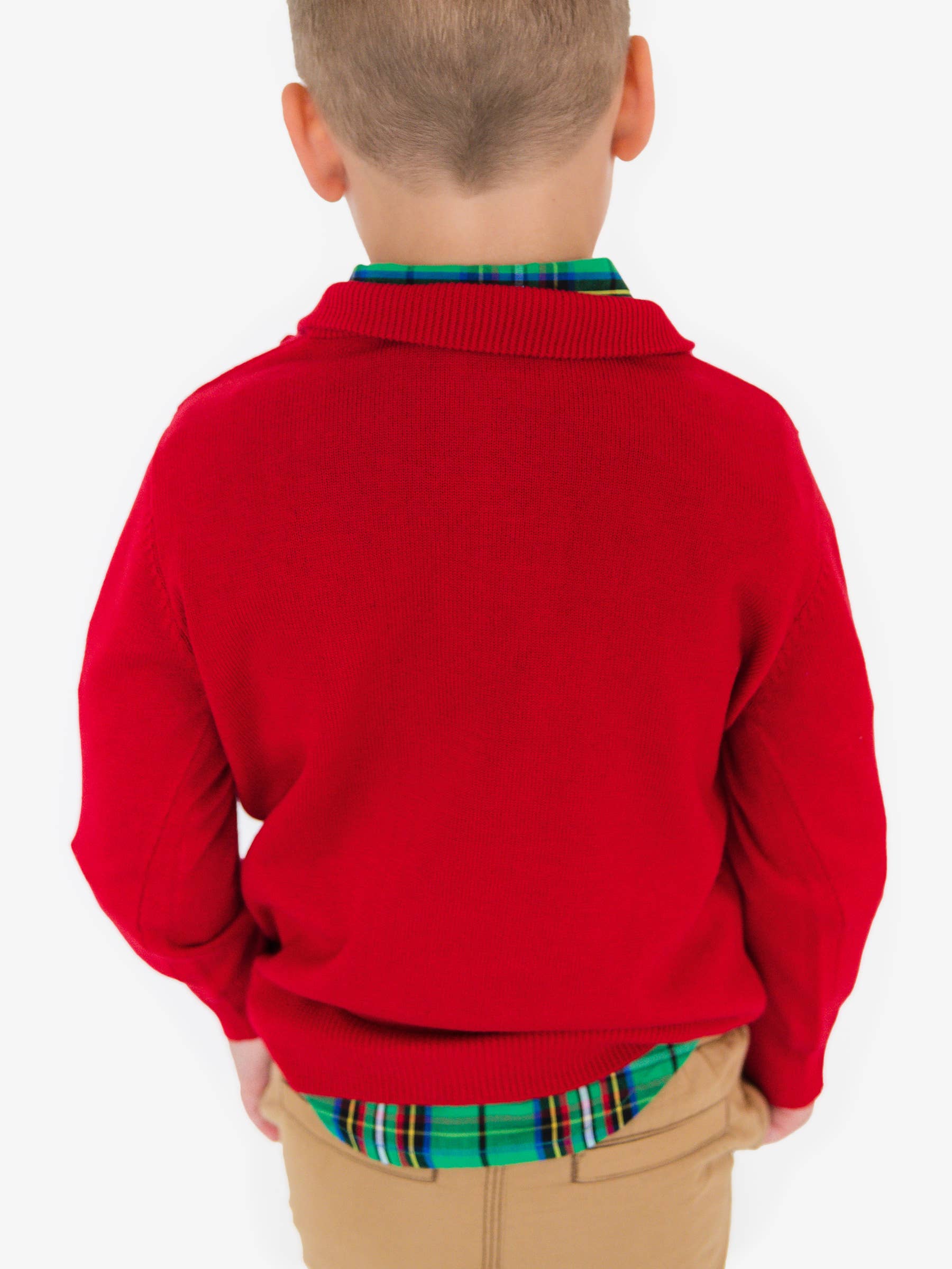 Child wearing a red sweater over a plaid shirt on a white background