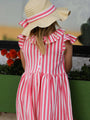 Person wearing a pink and white striped dress with a wide-brimmed hat in an outdoor setting.