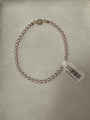 A single-strand pink pearl bracelet with a gold-toned decorative accent bead and a white product tag attached, displayed on a white textured surface.
