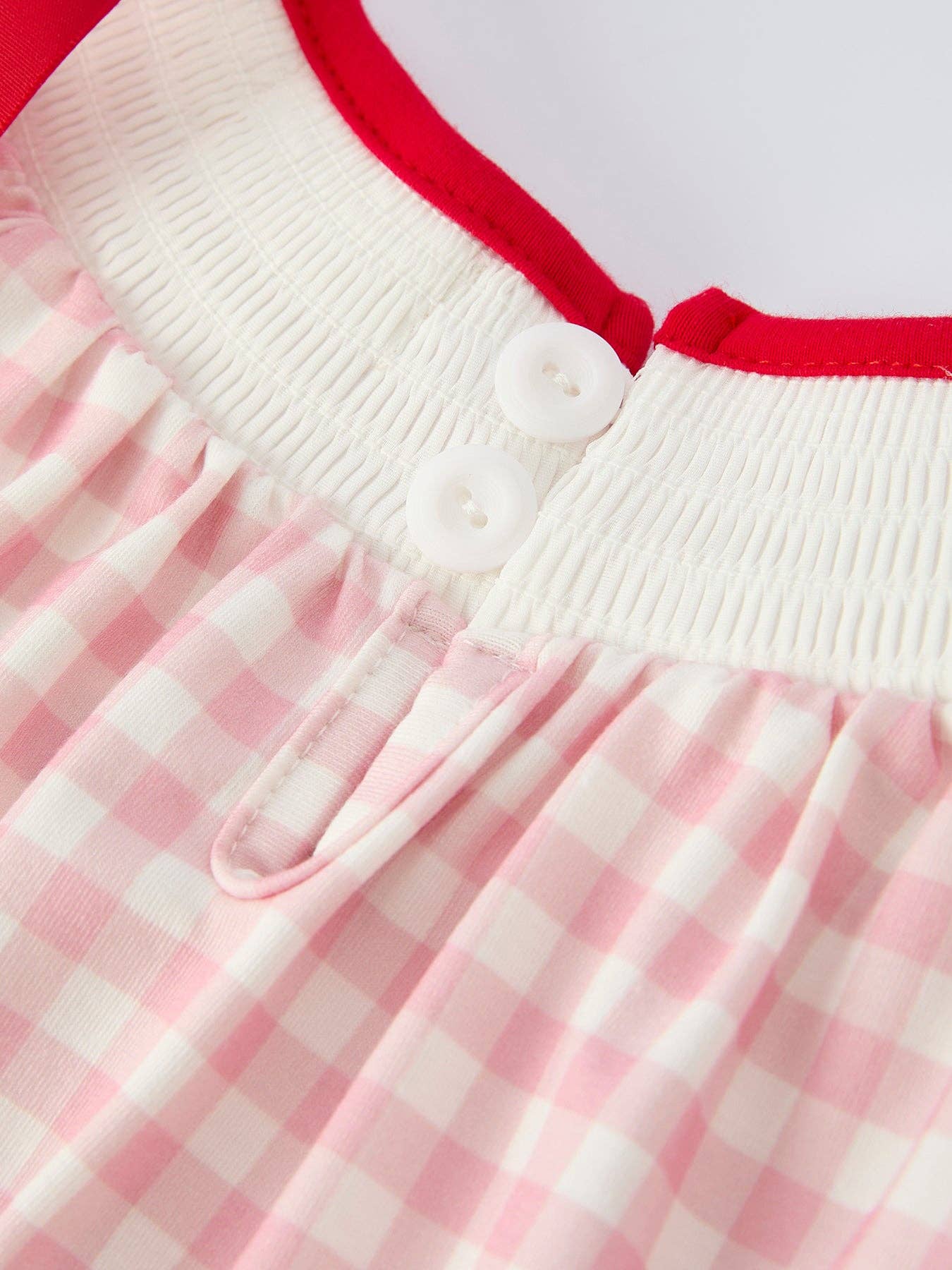 Close-up of a dress with pink and white checkered pattern and red trim.