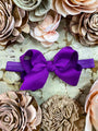 Purple hair bow on a textured surface with floral decorations