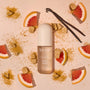Kitsch hair product bottle with vanilla beans and grapefruit slices on a beige background