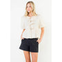 Woman wearing a white lace top and black shorts on a white background