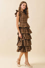 Woman wearing a tiered plaid dress on a beige background