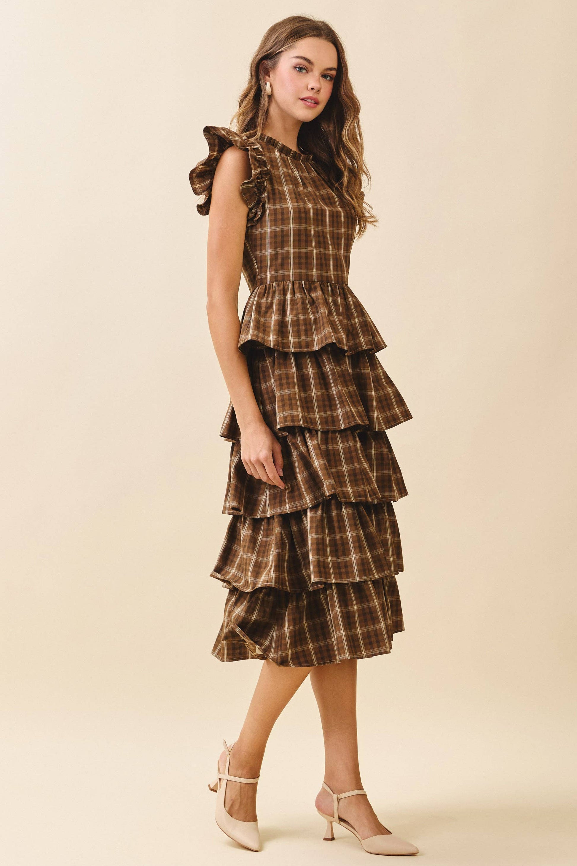 Woman wearing a tiered plaid dress on a beige background