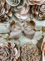 Close-up of beige floral and bow hair accessories on a textured surface