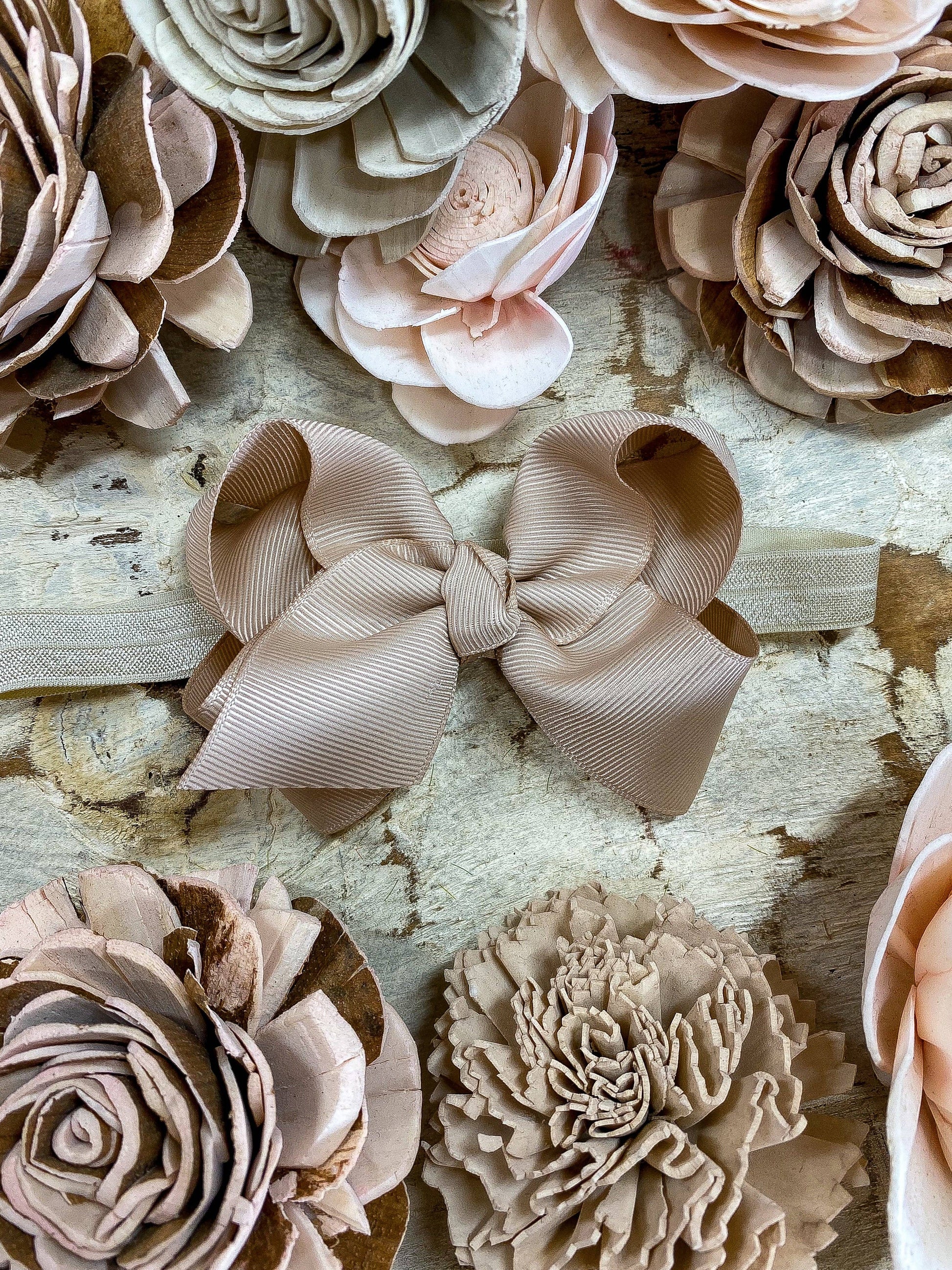 Close-up of beige floral and bow hair accessories on a textured surface