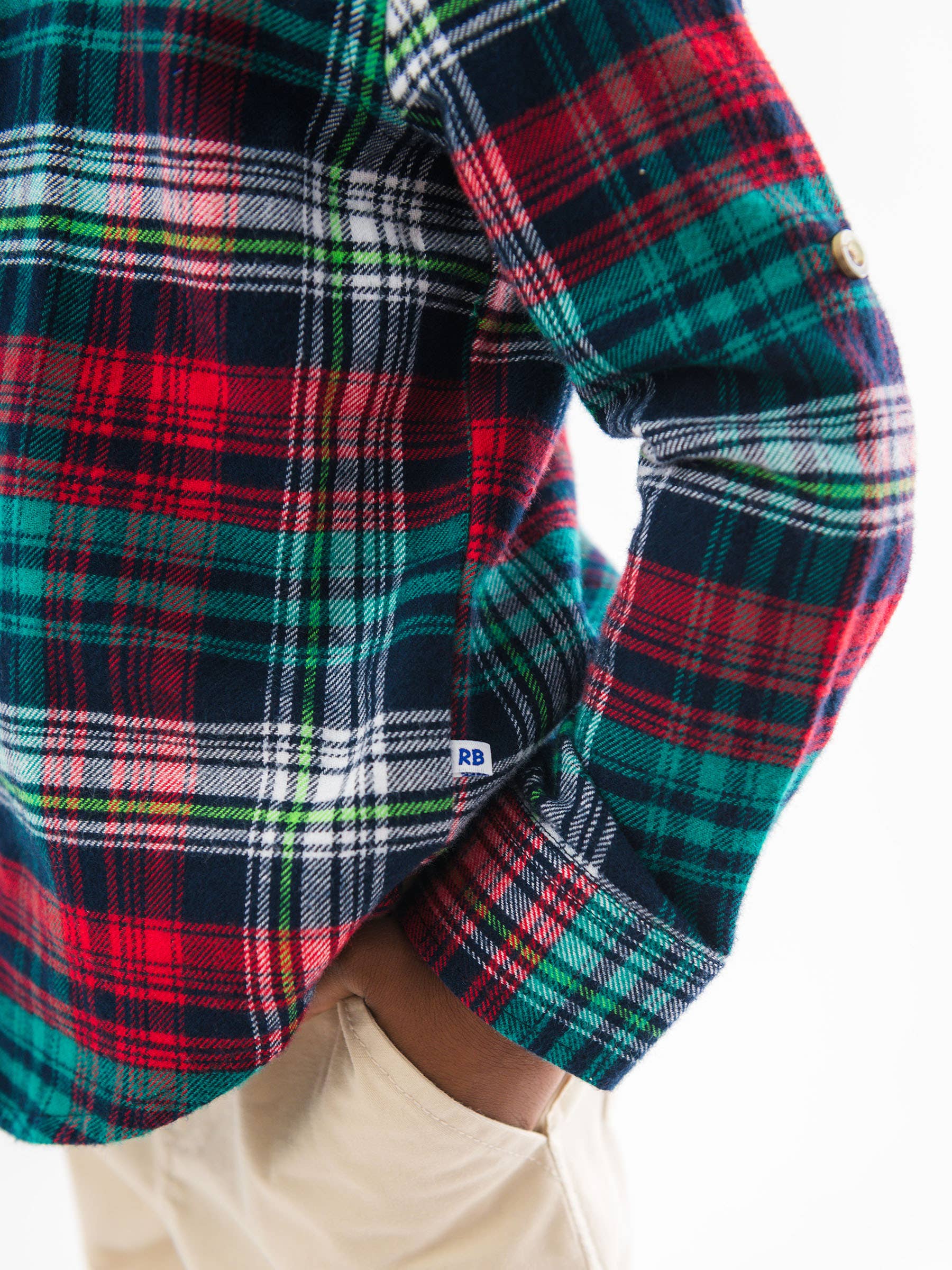Close-up of a plaid shirt with a visible brand logo on a white background