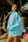 Person wearing a light blue sweatshirt with  text in a rustic outdoor setting