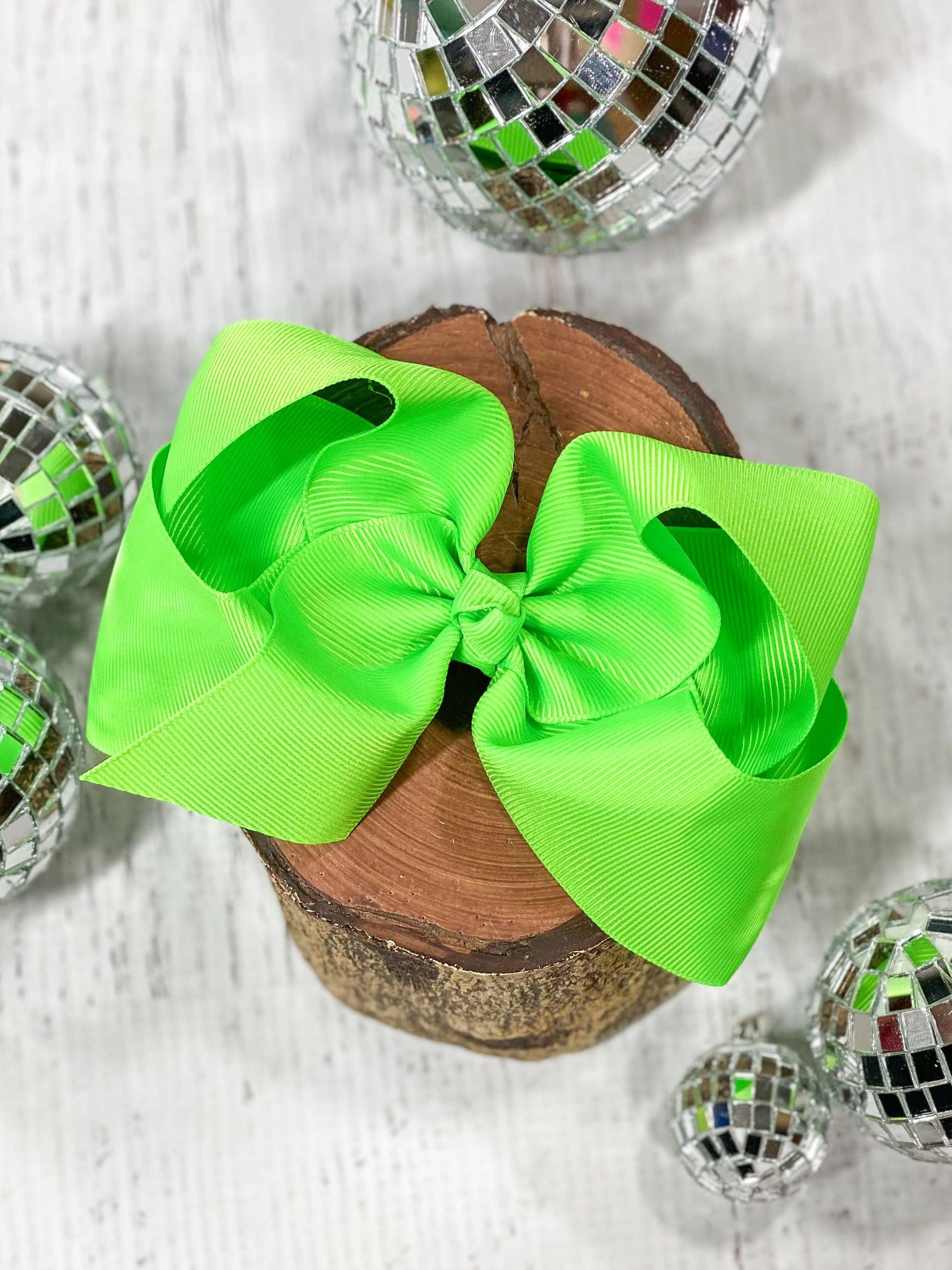 Two bright green bows on a wooden block with disco balls around