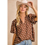 Woman wearing a brown polka dot blouse and white cowboy hat against a beige background