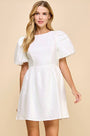 Woman wearing a white dress with puff sleeves against a beige background