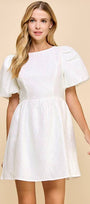 Woman wearing a white dress with puff sleeves against a beige background