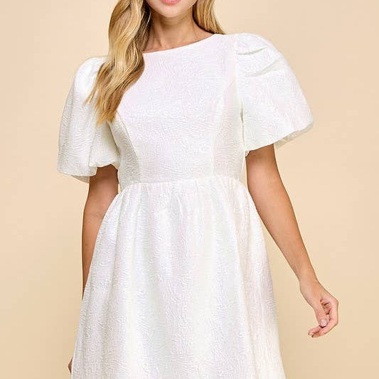 Woman wearing a white dress with puff sleeves against a beige background